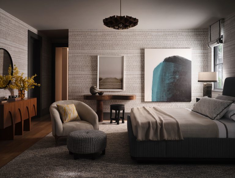 A modern bedroom with a large bed, beige bedding, and pillows, abstract art on the walls, a curved armchair with a plaid ottoman, a wooden console table with yellow flowers, a round mirror, and soft natural light from a window with blinds.